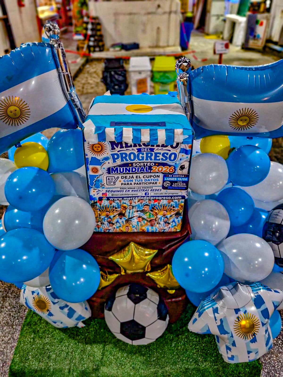 Urna del sorteo Mundial 2026 en el Mercado del Progreso, con decoración celeste y blanca
